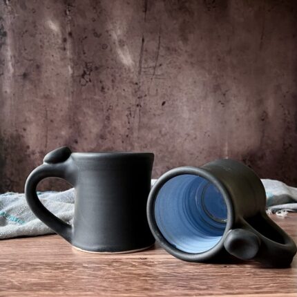 Ceramic coffee mug with thumb rest, glazed charcoal on exterior and sky blue on the interior.